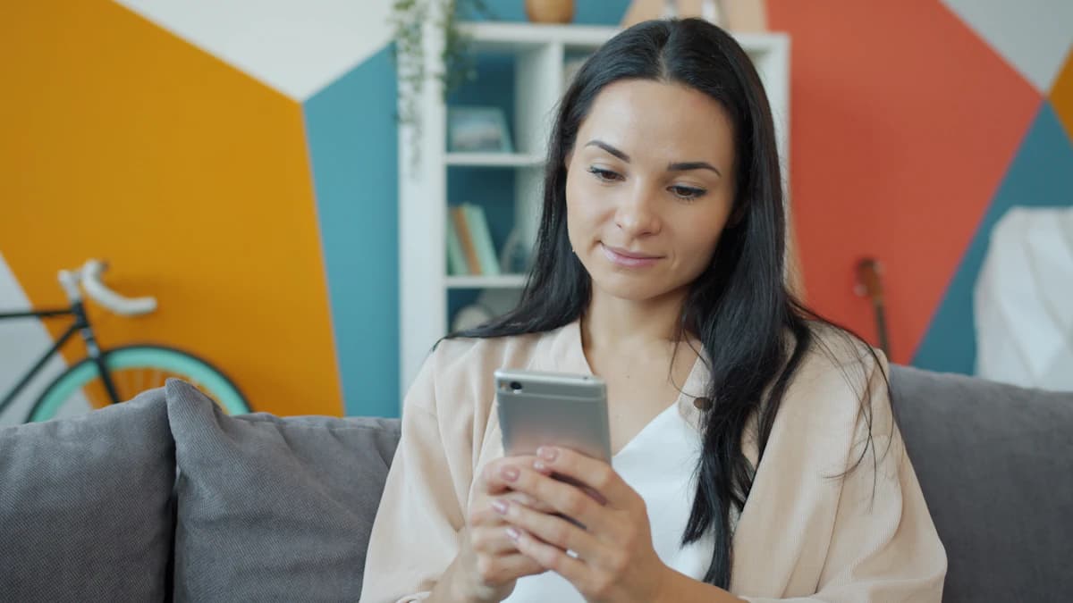 Someone smiling warmly while writing a message on their phone